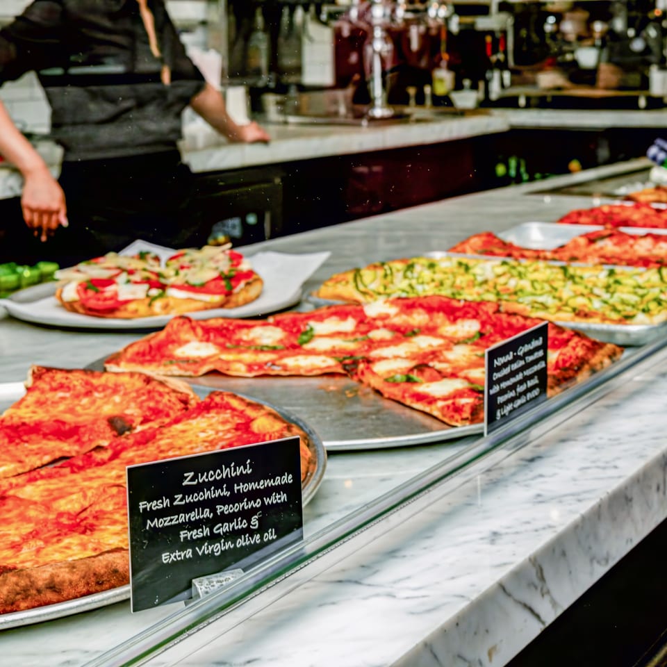 Assorted pizzas displayed at the La Villa Pizzeria counter.